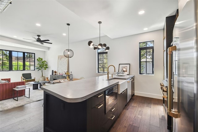 kitchen with a wealth of natural light, hanging light fixtures, dark hardwood / wood-style flooring, and stainless steel refrigerator