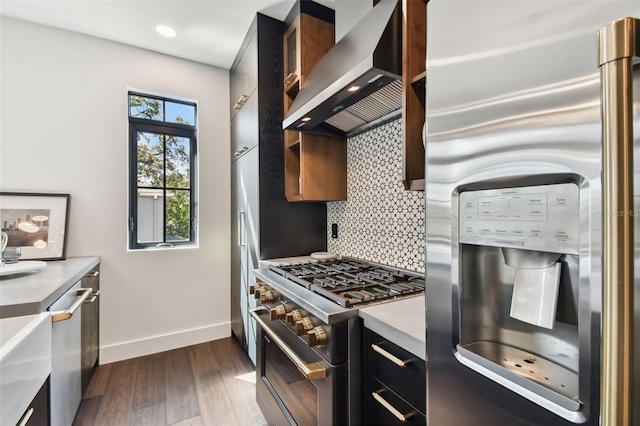 kitchen with tasteful backsplash, wall chimney range hood, stainless steel appliances, and dark hardwood / wood-style flooring