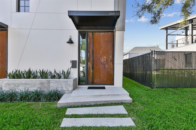 view of exterior entry with a lawn