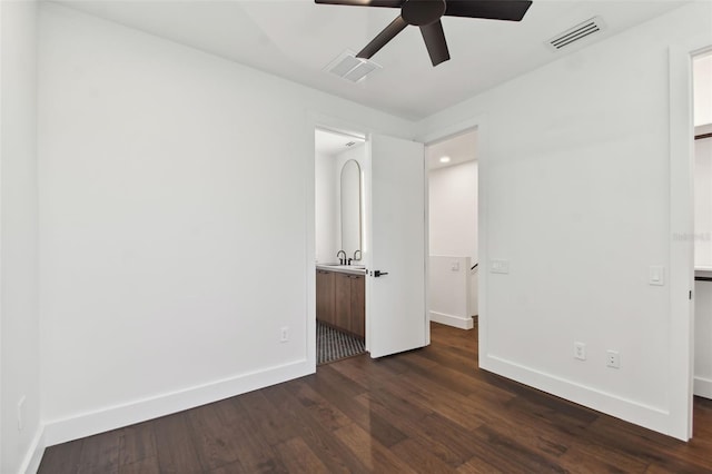 unfurnished bedroom featuring ensuite bath, sink, dark wood-type flooring, and ceiling fan