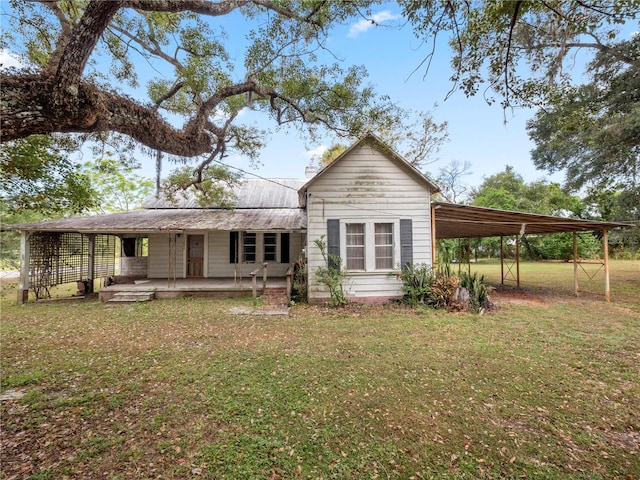 rear view of house featuring a carport and a yard