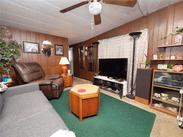 carpeted living room featuring wooden walls and ceiling fan