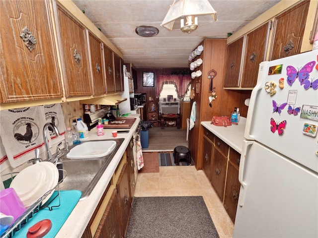 kitchen with light tile floors, a wall mounted air conditioner, sink, and white refrigerator