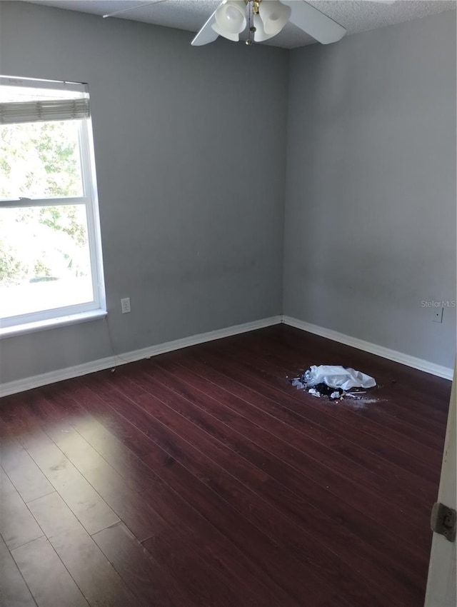 spare room with dark wood-type flooring, ceiling fan, and a textured ceiling