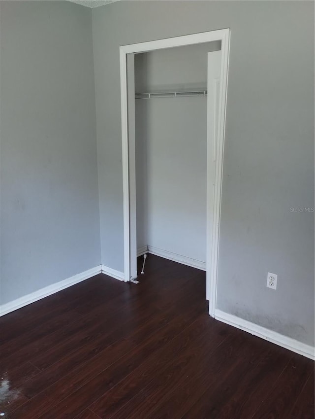 unfurnished bedroom with a closet and dark wood-type flooring