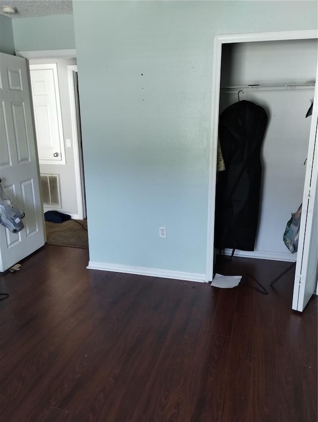 unfurnished bedroom with dark hardwood / wood-style floors and a closet