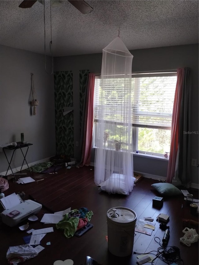 interior space with a textured ceiling, ceiling fan, and dark hardwood / wood-style floors