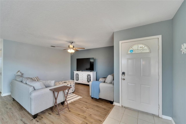 living room featuring light tile patterned floors, a textured ceiling, and ceiling fan