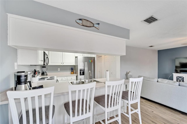 kitchen featuring white cabinetry, sink, light wood-type flooring, and appliances with stainless steel finishes