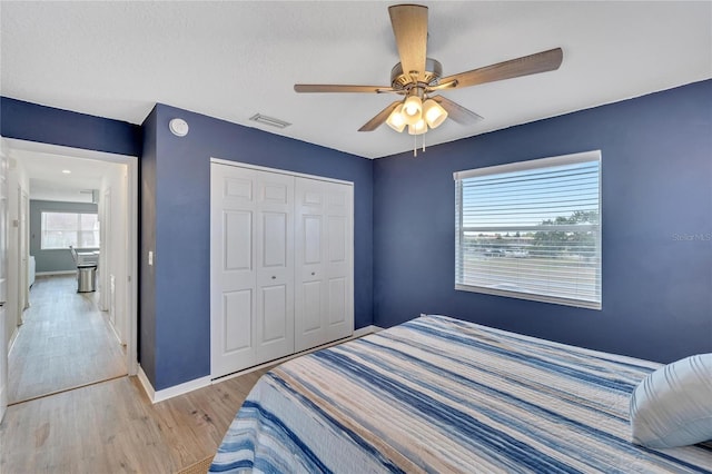 bedroom featuring light wood-type flooring, ceiling fan, and a closet