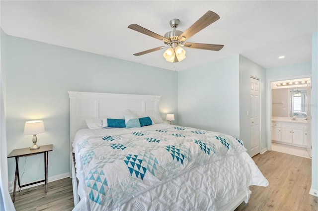 bedroom featuring light hardwood / wood-style flooring, ceiling fan, and ensuite bath