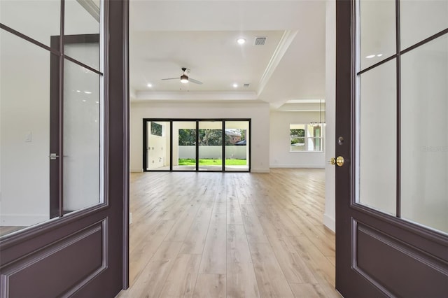 entryway with light hardwood / wood-style floors, a tray ceiling, ornamental molding, and ceiling fan