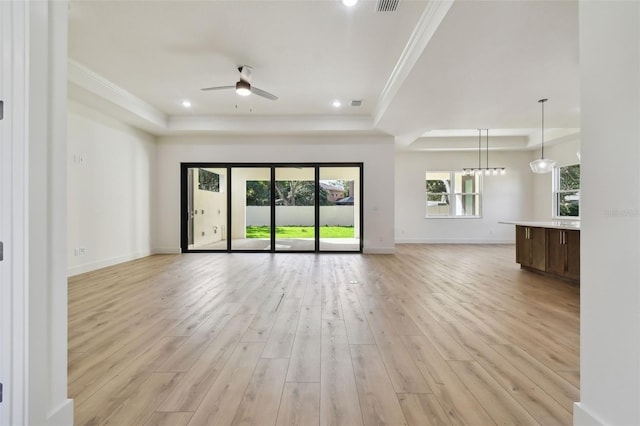 unfurnished living room featuring ceiling fan, crown molding, a tray ceiling, and light hardwood / wood-style flooring