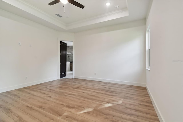 unfurnished room with light hardwood / wood-style floors, a tray ceiling, and crown molding