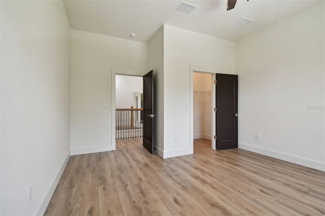 unfurnished bedroom with ceiling fan, light hardwood / wood-style flooring, a closet, and a spacious closet