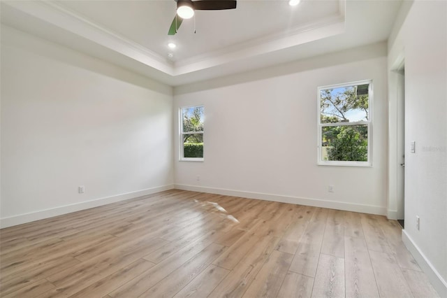 spare room with ceiling fan, plenty of natural light, light hardwood / wood-style flooring, and a raised ceiling