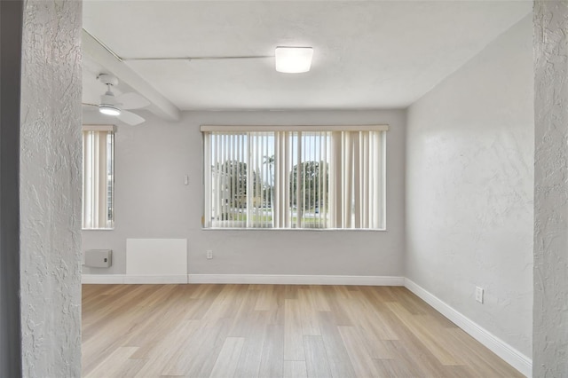 unfurnished room featuring ceiling fan, light hardwood / wood-style flooring, and beamed ceiling