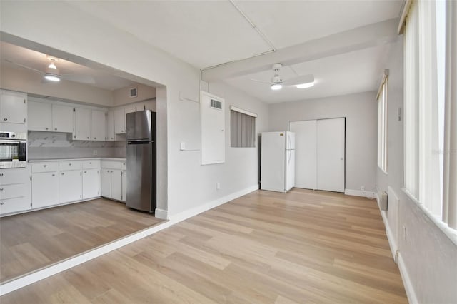 kitchen featuring stainless steel appliances, ceiling fan, white cabinetry, backsplash, and light wood-type flooring