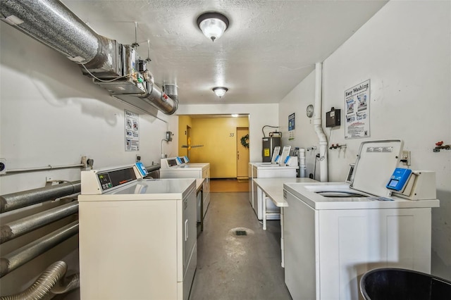 clothes washing area with electric water heater, washing machine and dryer, and a textured ceiling