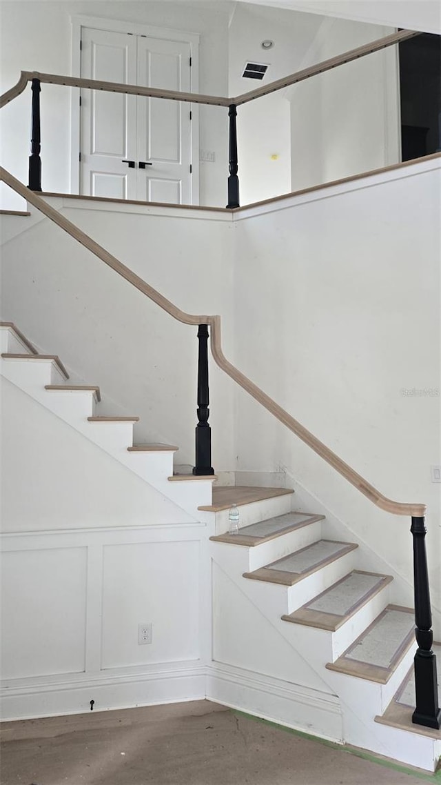 stairway with a decorative wall and wood finished floors