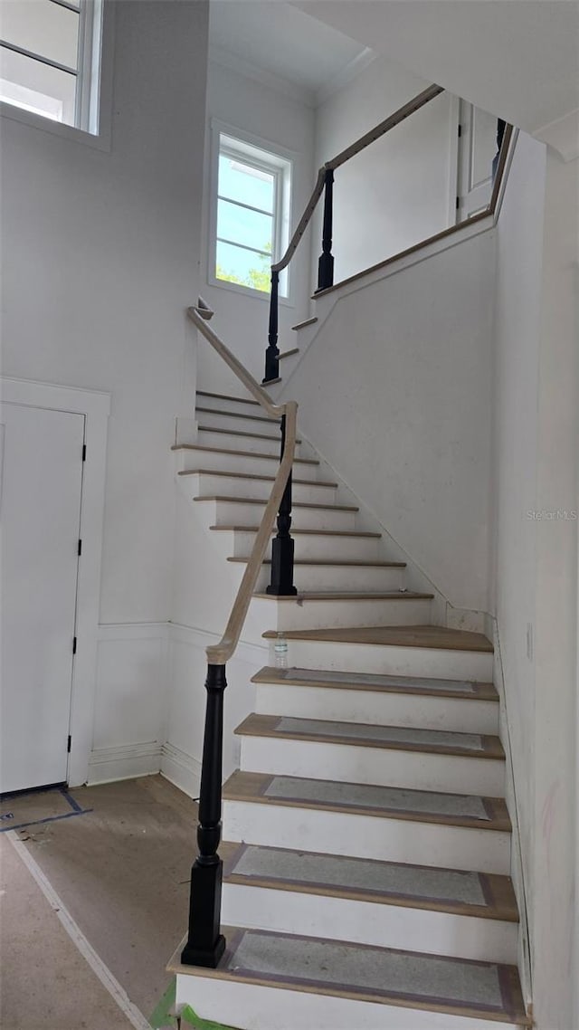 stairway with concrete floors and crown molding