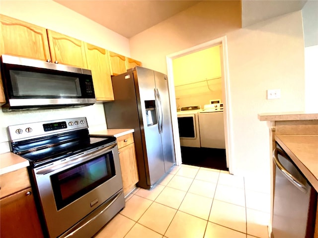 kitchen with separate washer and dryer, light tile patterned flooring, and appliances with stainless steel finishes