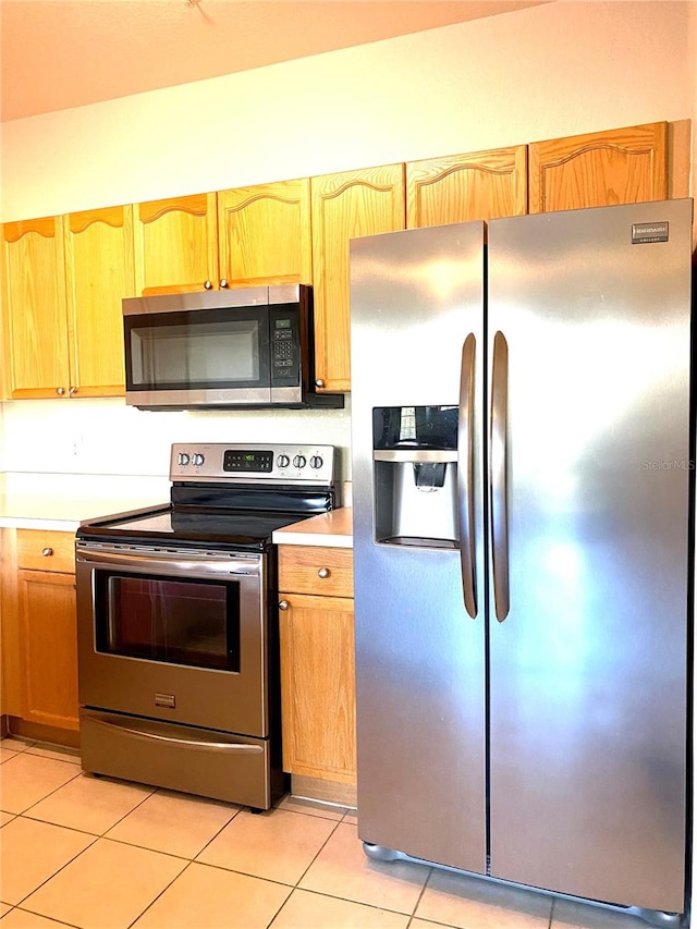 kitchen featuring stainless steel appliances and light tile patterned flooring