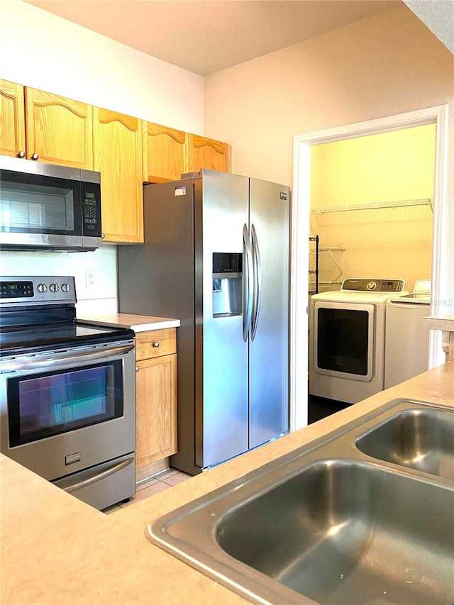 kitchen with washing machine and clothes dryer, appliances with stainless steel finishes, and sink