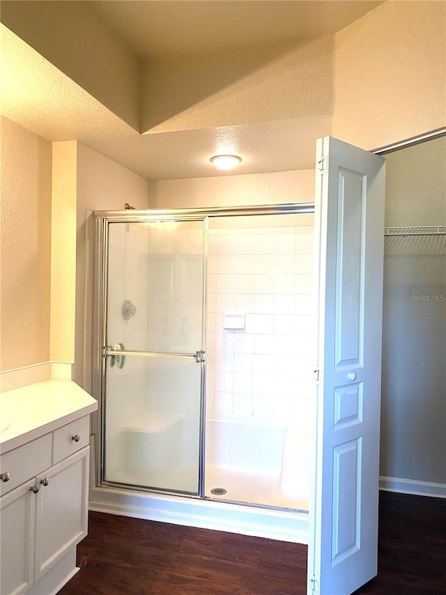 bathroom featuring walk in shower, vanity, hardwood / wood-style floors, and a textured ceiling