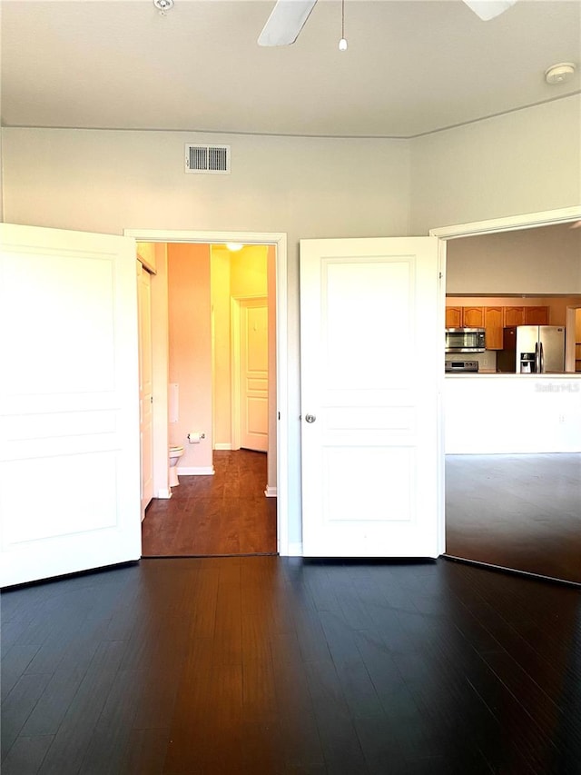 interior space featuring stainless steel refrigerator with ice dispenser, connected bathroom, ceiling fan, and dark hardwood / wood-style flooring