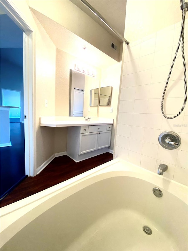 bathroom with tiled shower / bath combo, vanity, and wood-type flooring