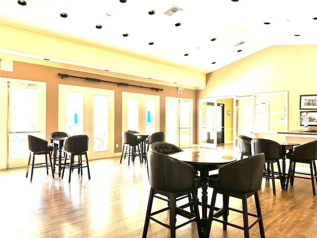 dining area featuring vaulted ceiling, french doors, and light wood-type flooring