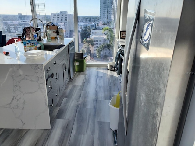 kitchen with appliances with stainless steel finishes, light wood-type flooring, a kitchen island, and gray cabinetry