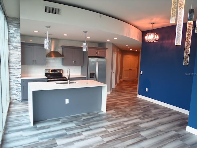 kitchen featuring sink, hanging light fixtures, wall chimney exhaust hood, light wood-type flooring, and stainless steel appliances