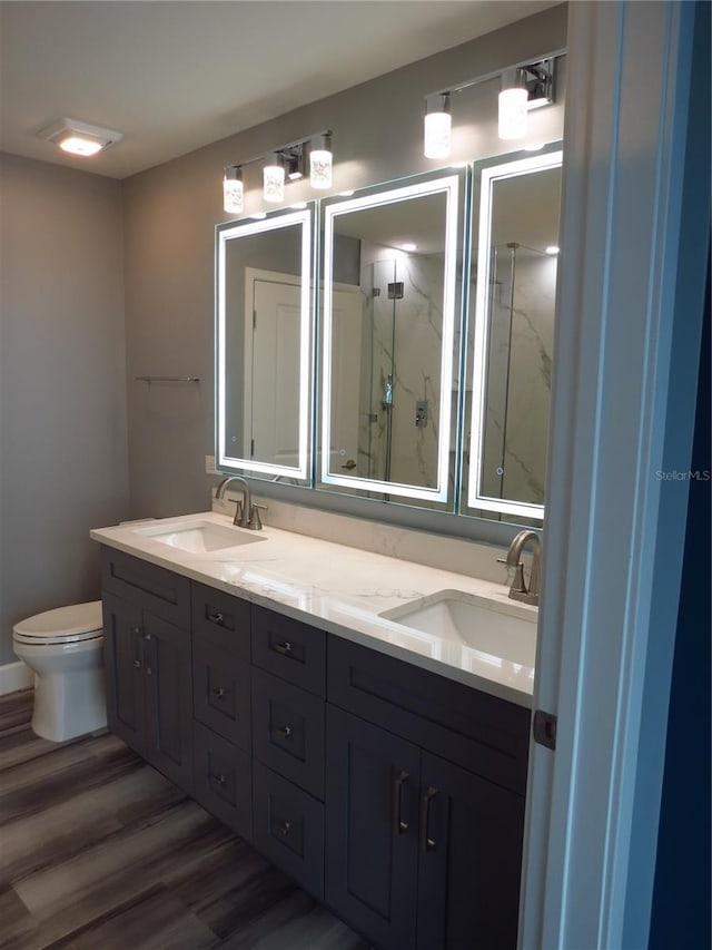 bathroom featuring toilet, hardwood / wood-style floors, vanity, and walk in shower