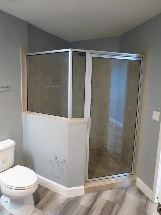 bathroom featuring hardwood / wood-style floors, a shower with shower door, and toilet