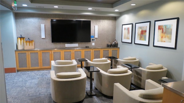 home theater room featuring dark colored carpet and a raised ceiling