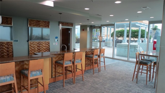 bar featuring pendant lighting, a healthy amount of sunlight, light carpet, and dark stone counters