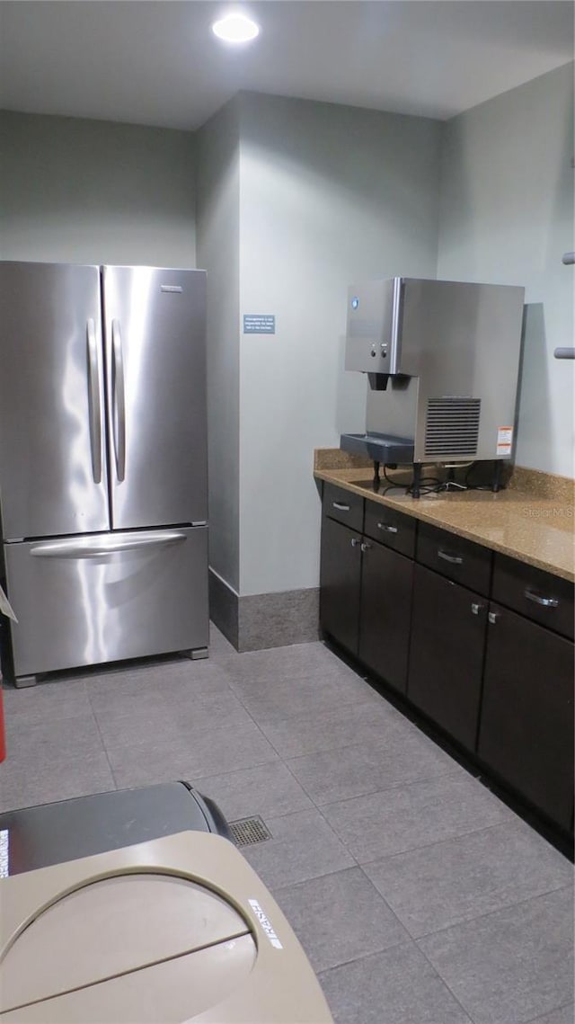 kitchen featuring light stone counters, stainless steel refrigerator, and light tile patterned flooring