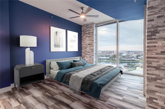 bedroom with ceiling fan, expansive windows, a water view, and multiple windows