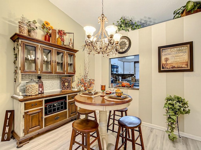 dining space featuring vaulted ceiling, light hardwood / wood-style flooring, and an inviting chandelier