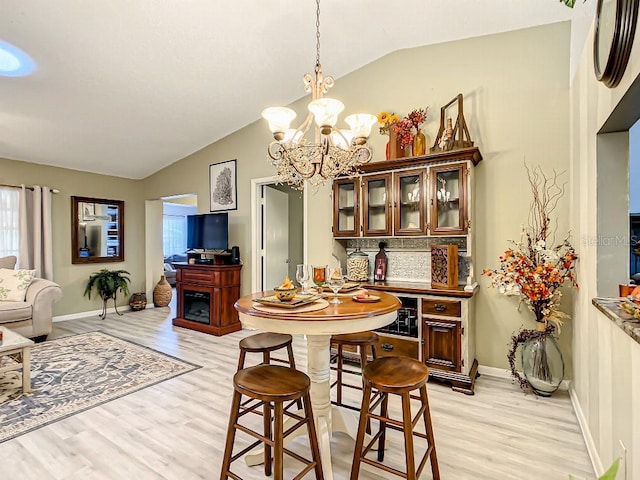 dining space featuring a chandelier, vaulted ceiling, and light hardwood / wood-style flooring