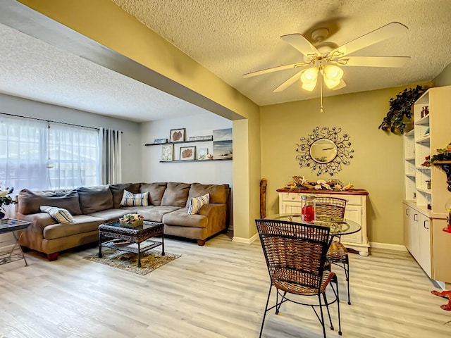 living room featuring light hardwood / wood-style floors, a textured ceiling, and ceiling fan