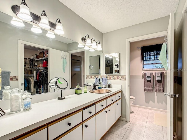 bathroom with toilet, tile flooring, a textured ceiling, and vanity