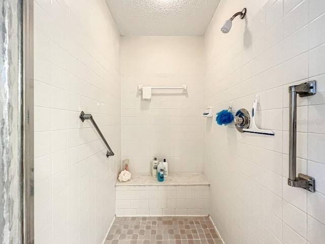 bathroom featuring a tile shower and a textured ceiling