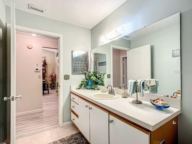 bathroom featuring vanity with extensive cabinet space, tile flooring, and a textured ceiling