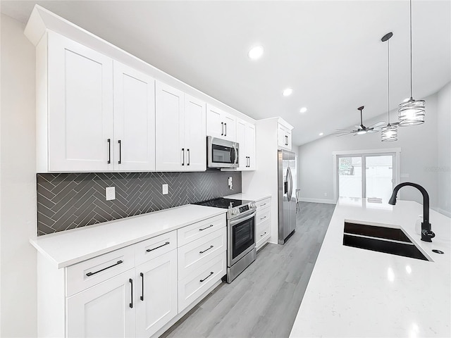 kitchen featuring sink, white cabinetry, vaulted ceiling, appliances with stainless steel finishes, and pendant lighting