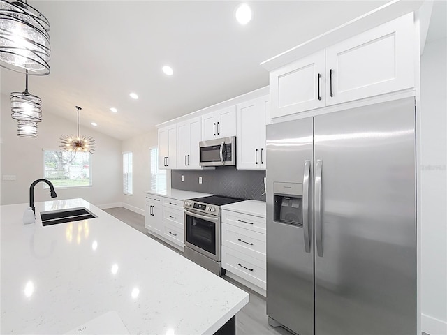 kitchen with lofted ceiling, sink, hanging light fixtures, stainless steel appliances, and white cabinets