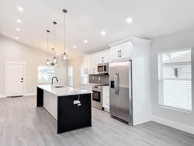 kitchen featuring sink, hanging light fixtures, a center island with sink, stainless steel appliances, and white cabinets