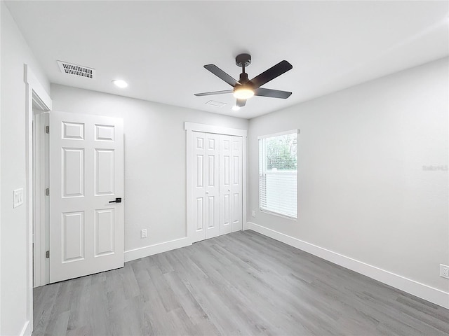 unfurnished bedroom with light wood-type flooring, ceiling fan, and a closet